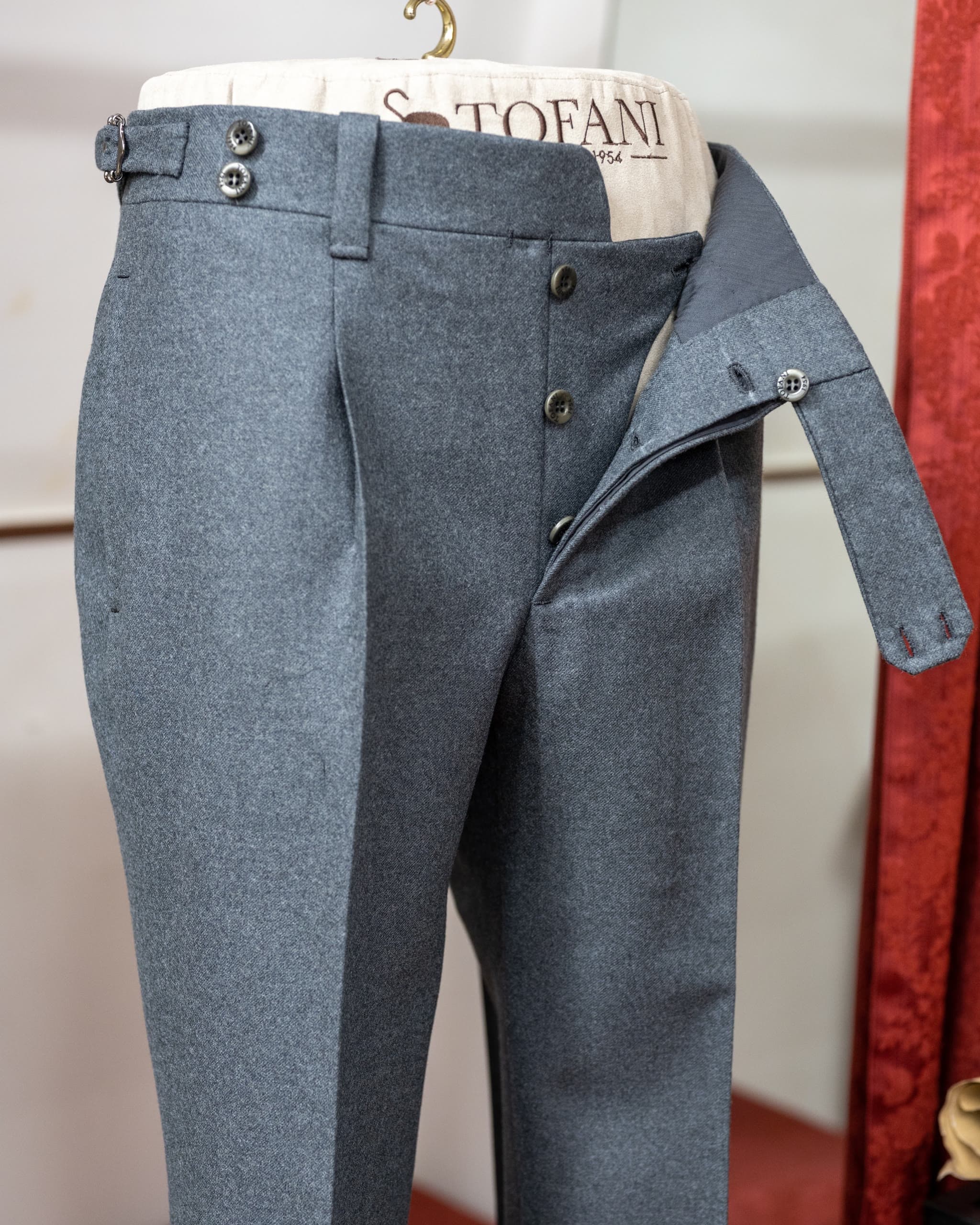 Grey tailored trousers displayed open at the fly on a Sartoria Tofani form.
