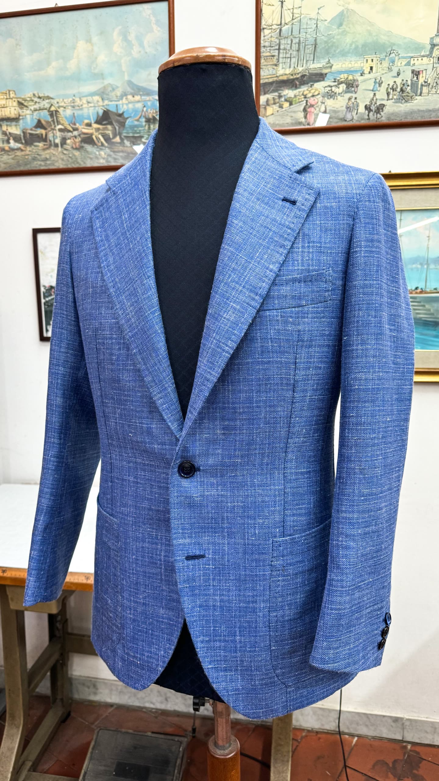 A finished blue textured single-breasted jacket displayed on a tailor’s form.