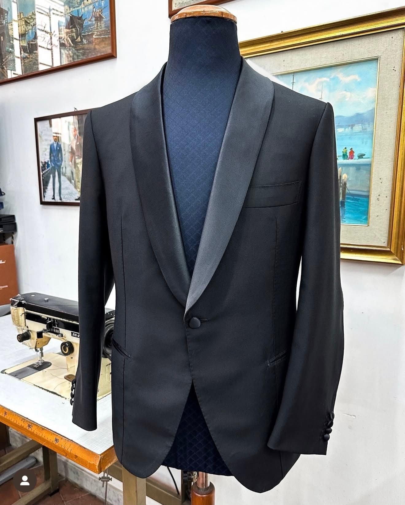 A black bespoke tuxedo jacket with a satin shawl lapel, displayed on a tailor’s form in Naples.