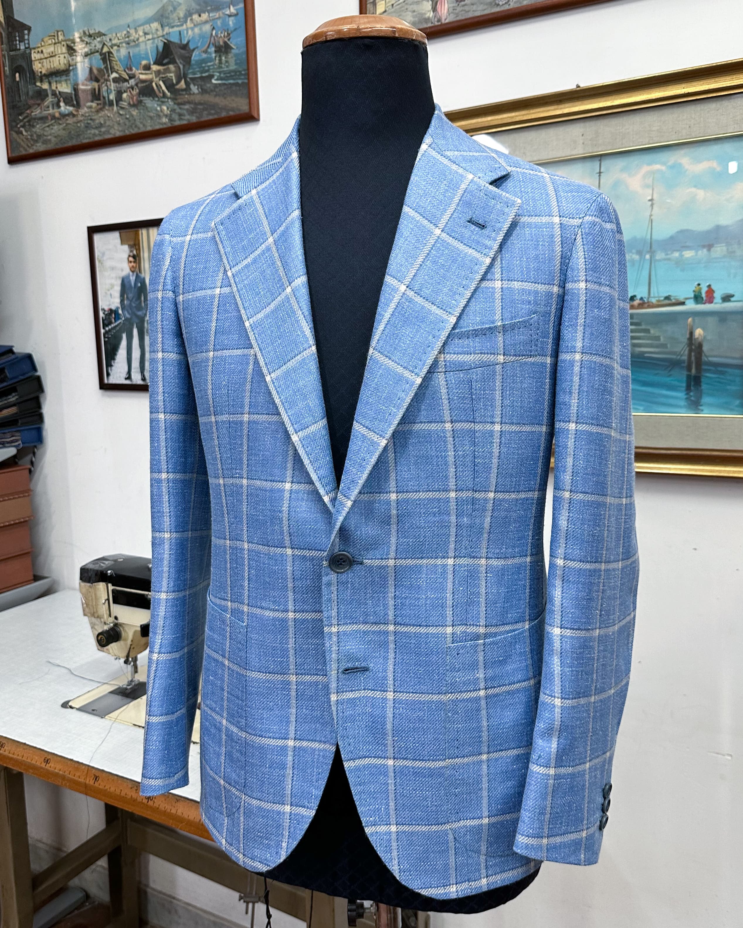 A light-blue windowpane tailored jacket with patch pockets, displayed on a tailor’s form.