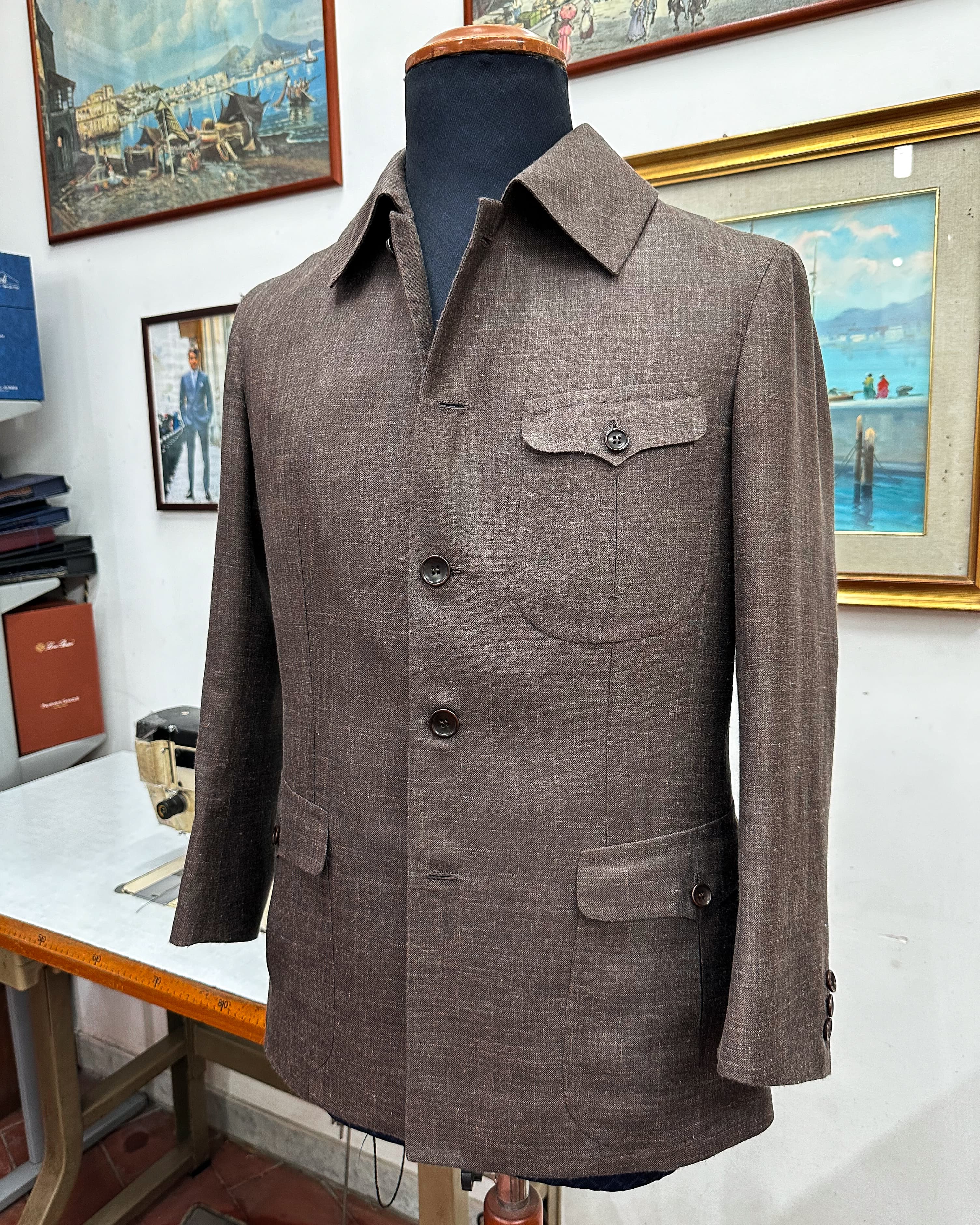 A brown textured safari jacket with flap pockets, displayed on a tailor’s form in Naples.